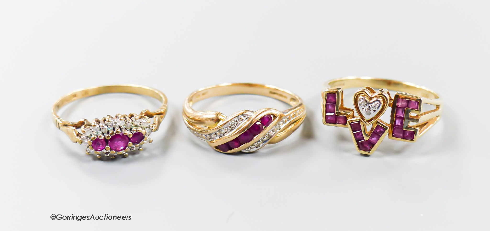 Three modern 9ct gold, ruby and diamond set dress rings including a 'Love' ring, size O, gross weight 5.7 grams.